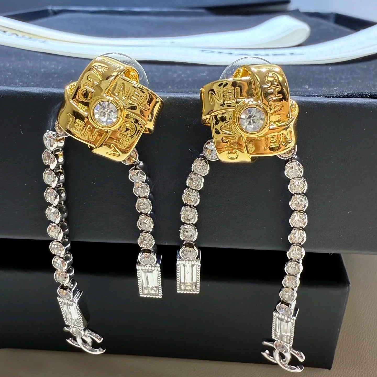 Gold and silver earrings with gemstones on a black stand.