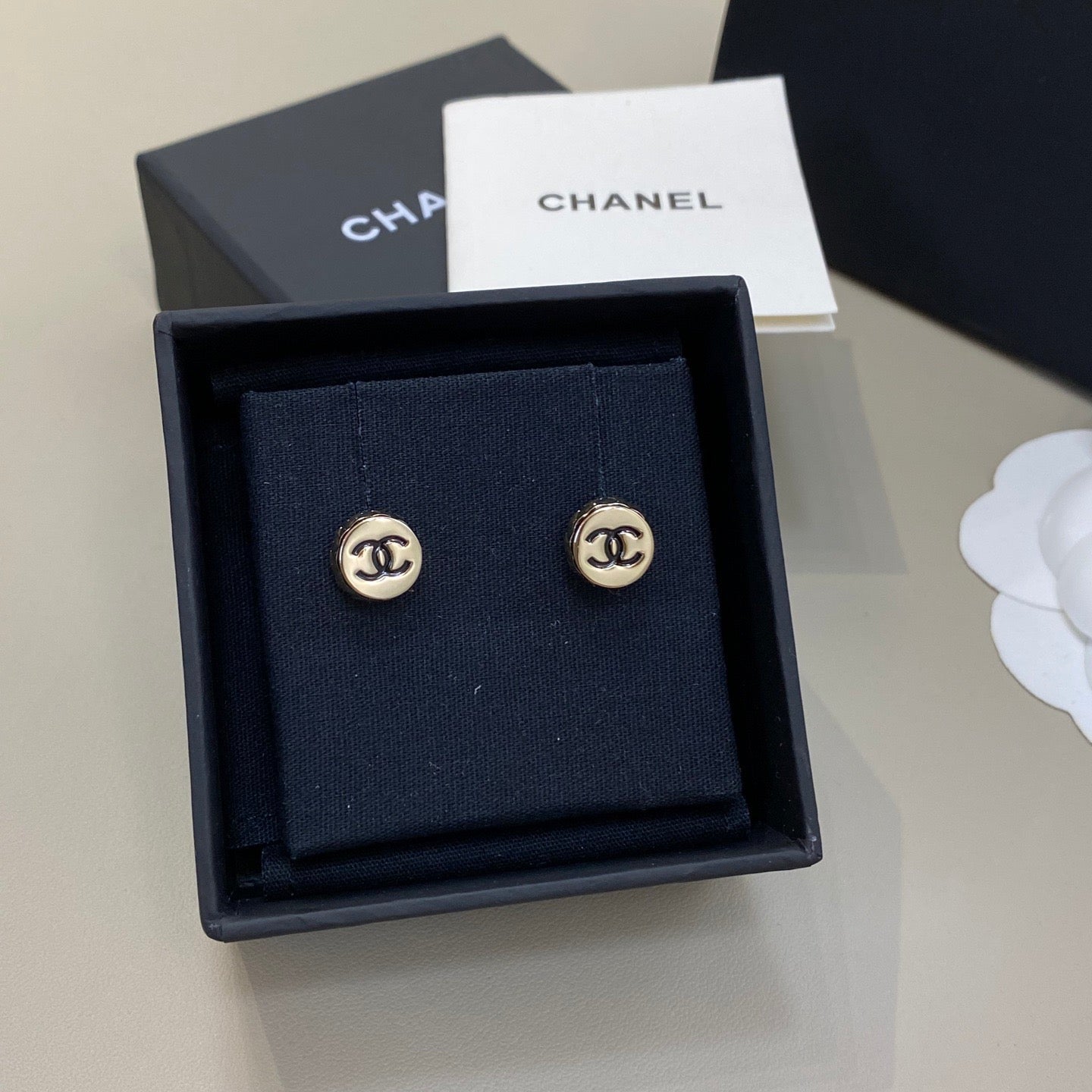 Chanel earrings in a black box with a Chanel card on a light gray background