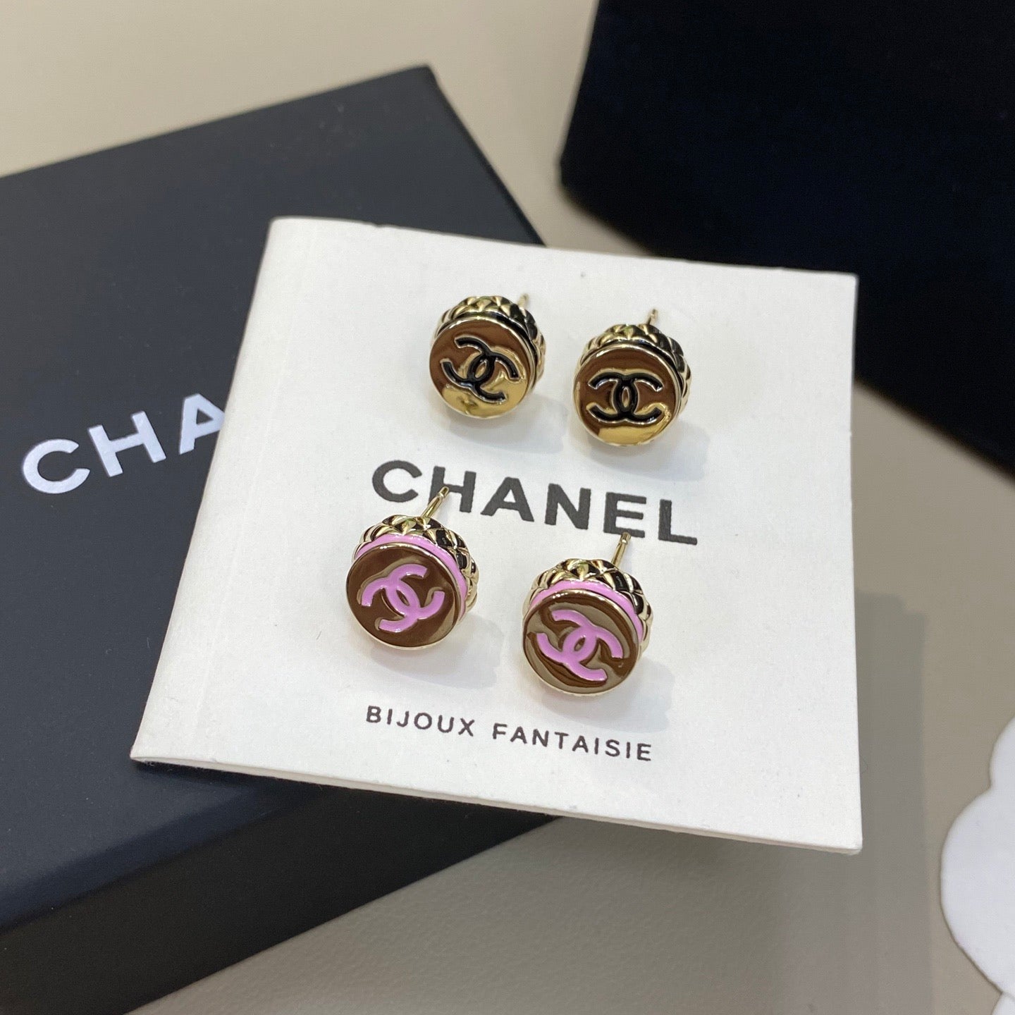Chanel earrings on a branded card with a black box in the background