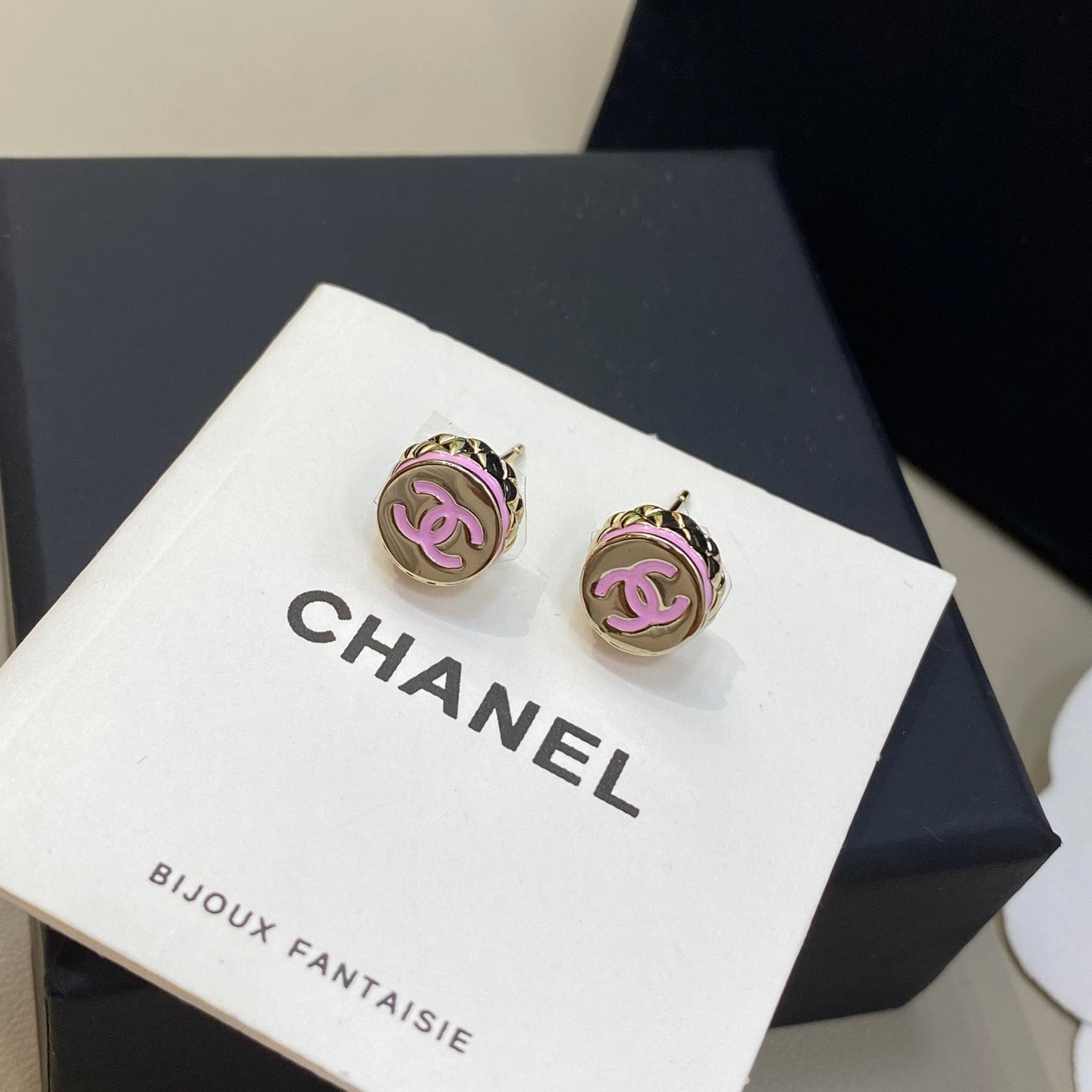 Chanel earrings on a branded display card with a black box in the background