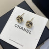 Gold Chanel earrings on a branded display card