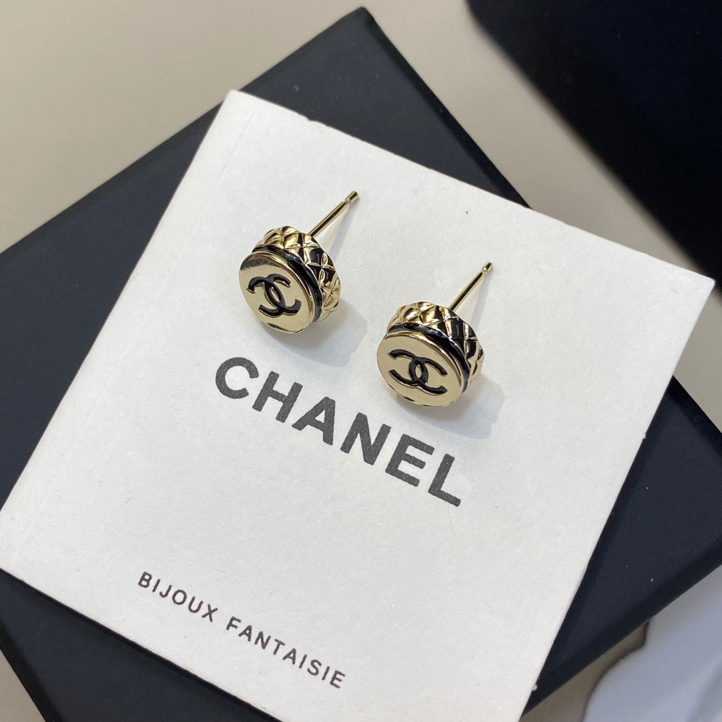 Gold Chanel earrings on a branded display card