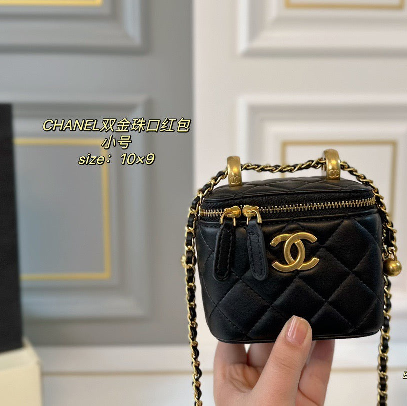 Black quilted handbag with gold chain and hardware held by a hand against a neutral background