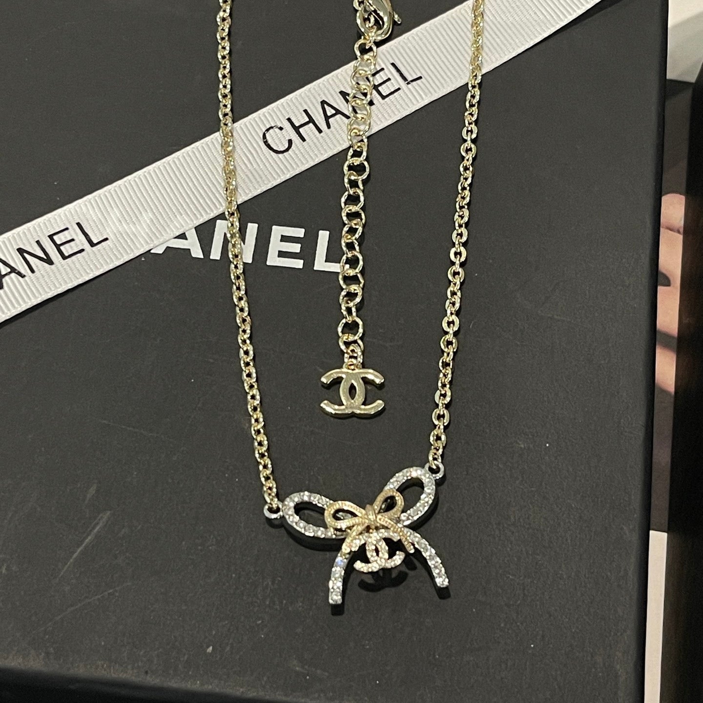 Gold necklace with bow pendant on a Chanel branded box
