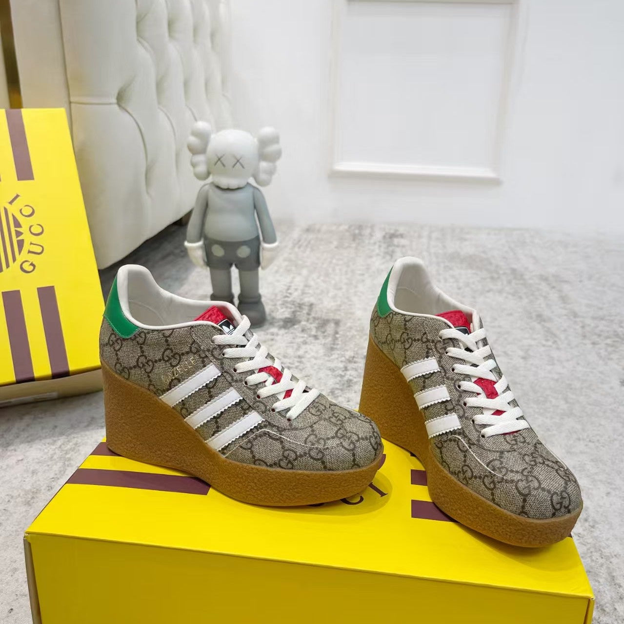 Pair of Gucci sneakers on a yellow box with a white wall and gray floor in the background.