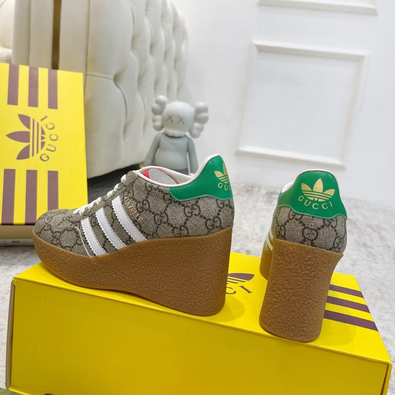 Gucci and Adidas shoes on a yellow box with Gucci logo.