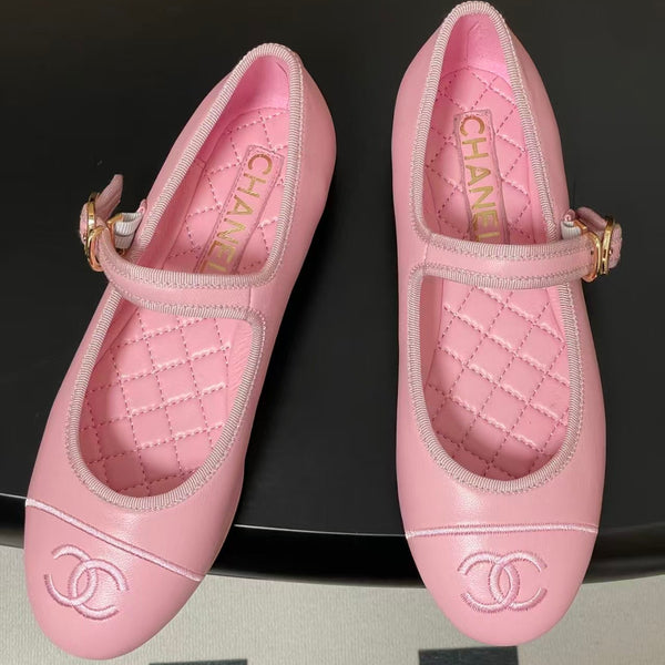 Pair of pink quilted shoes with Chanel logo on a black background